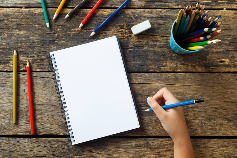 caderno e lápis coloridos sb mesa de madeira